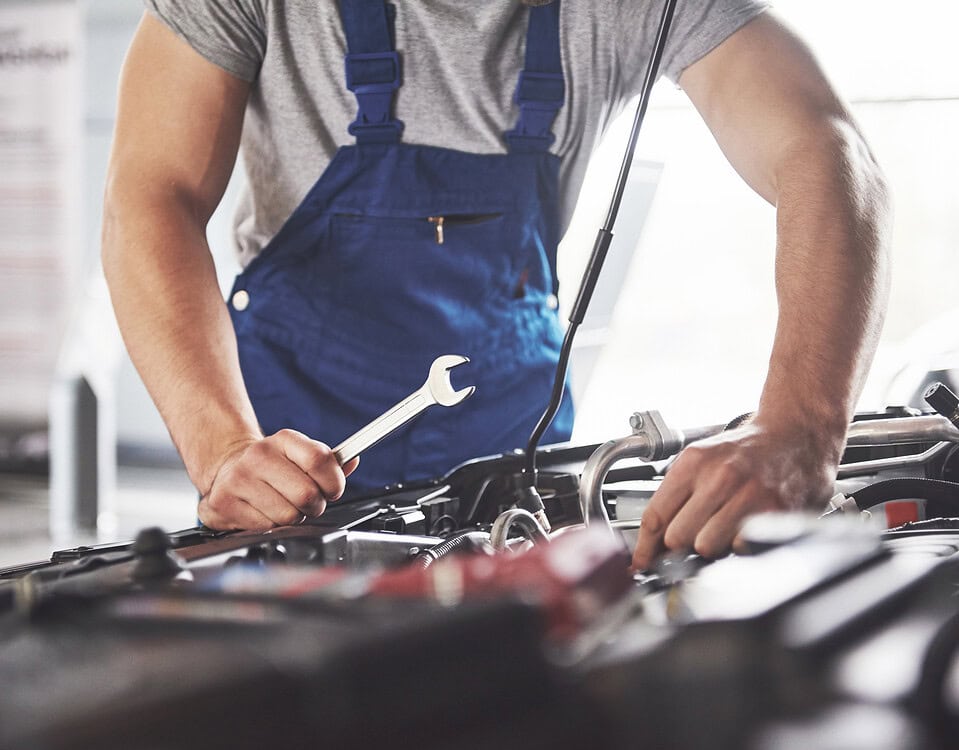 Muscular car service worker repairing vehicle.